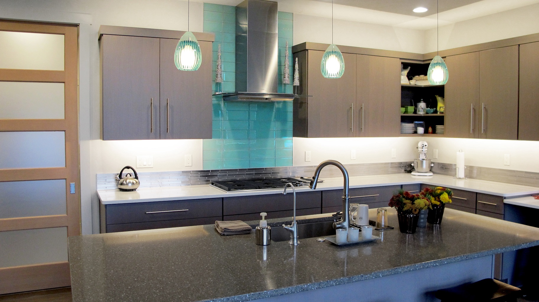 Aqua Blue Crystile 4x12 glass field tile Glazzio Soft Mint above a gas cook top arctic grey cabinets in the kitchen with Pental quartz perimeter. 