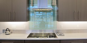 Aqua Blue Crystile 4x12 glass field tile Glazzio Soft Mint above a gas cook top arctic grey cabinets in the kitchen with Pental quartz perimeter.