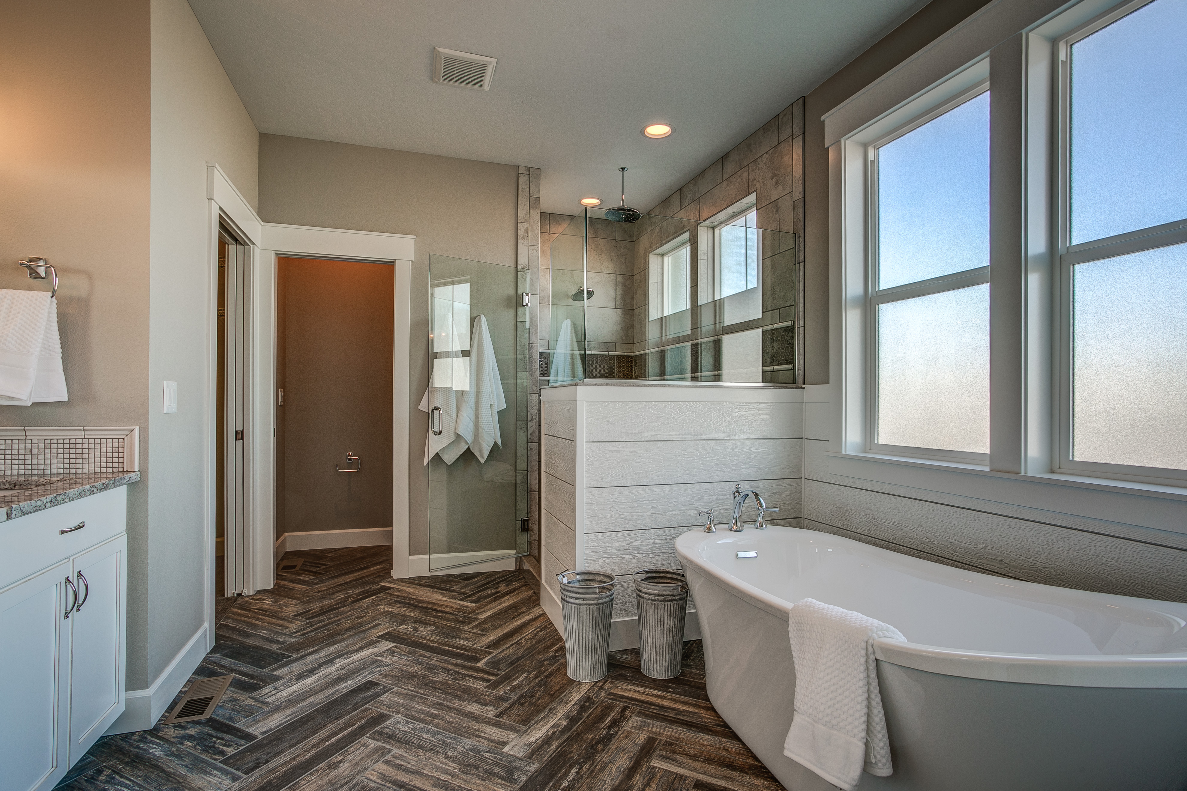Master bathroom free-standing tub herringbone tile floor walk-in shower wainscot
