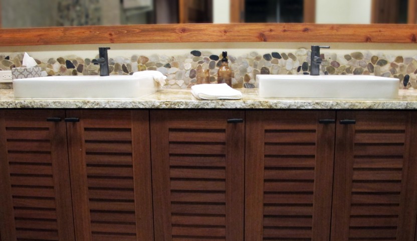 Second master bathroom rivera multi color pebble backsplash with granite countertops and overmount white porcelain sinks. dark cherry stained cabinets and alder wood mirror over the top