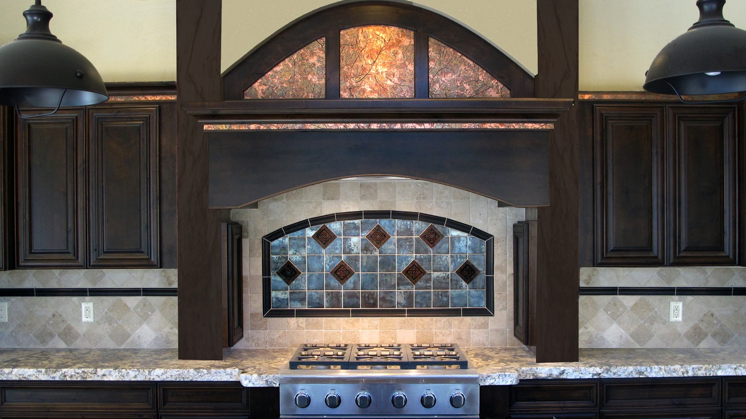 Kitchen rustic espresso cabinets custom arch gas range cook top granite countertops  travertine backsplash natural stone light beige metal metallic chair rail arch stove accent Emser Statements