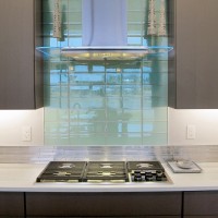 Aqua Blue Crystile 4x12 glass field tile Glazzio Soft Mint above a gas cook top arctic grey cabinets in the kitchen with Pental quartz perimeter.