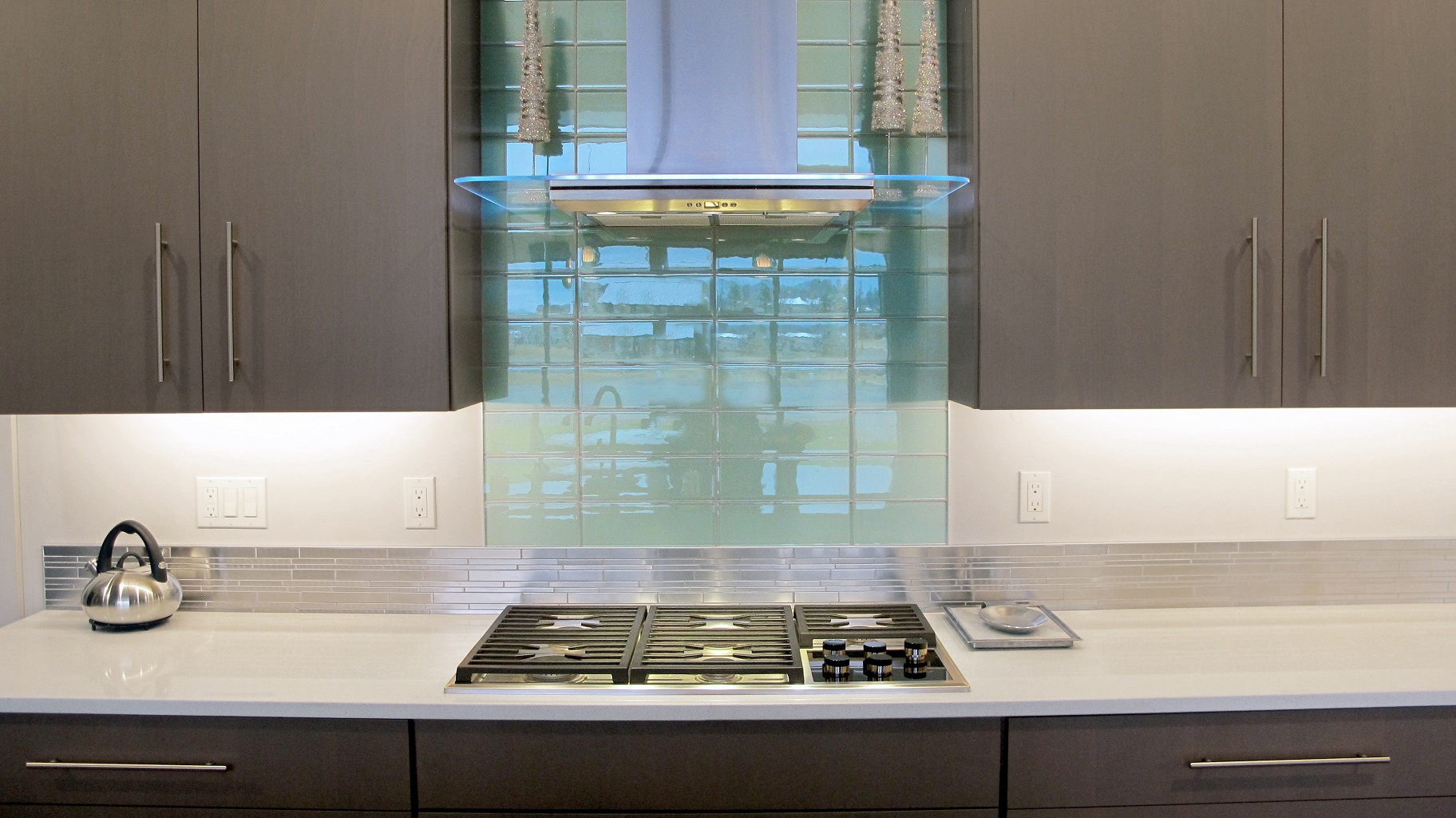 Aqua Blue Crystile 4x12 glass field tile Glazzio Soft Mint above a gas cook top arctic grey cabinets in the kitchen with Pental quartz perimeter. 
