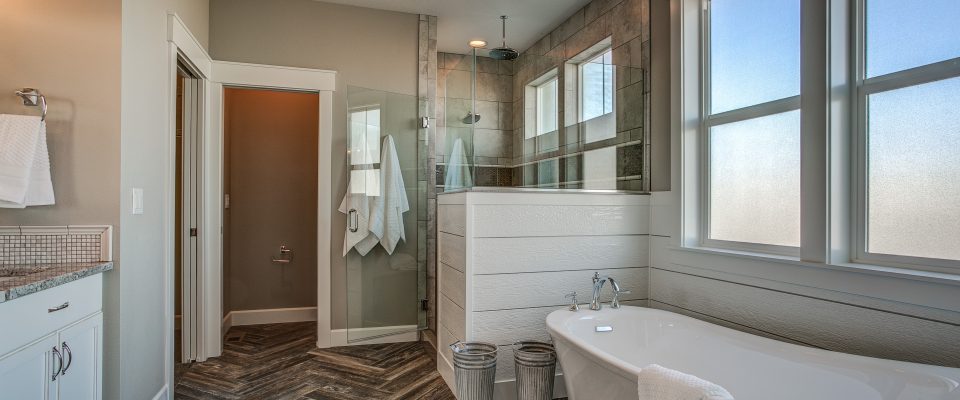 Master bathroom free-standing tub herringbone tile floor walk-in shower wainscot